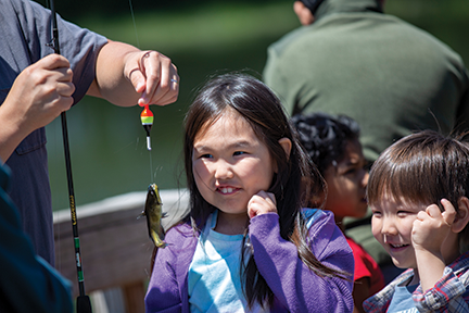 Girl looking at a small fish on a hook.