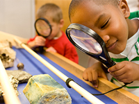 Two kids using magnifying glasses.