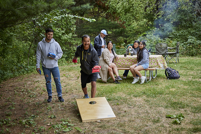 Hispanic family playing bean bags at a campsite.